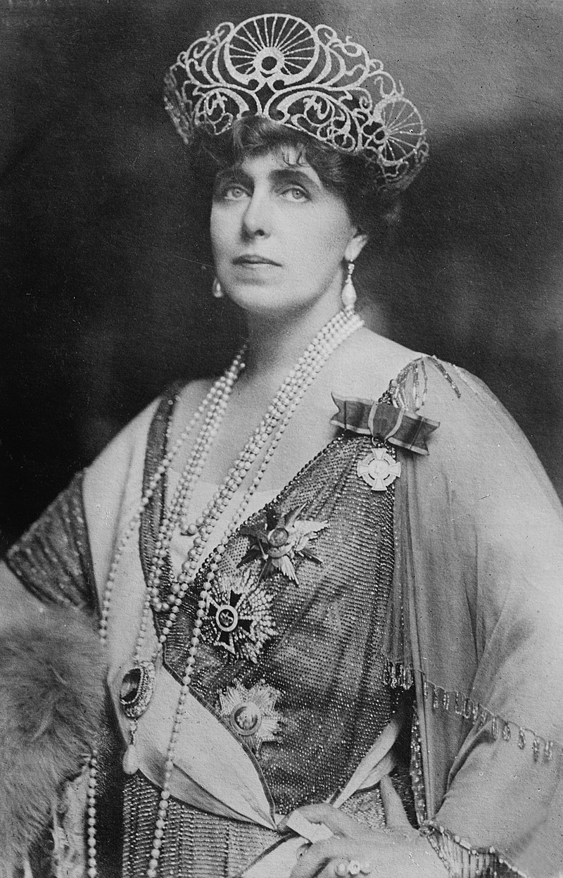 Fotografia portretowa przedstawia osobę królowej Marii w jasnej sukni, z przypiętymi orderami. Na głowie ułożona jest korona.&nbsp;